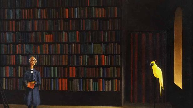 Ein Mann mit Brille steht in einer Bibliothek neben einem gelben Kakadu.