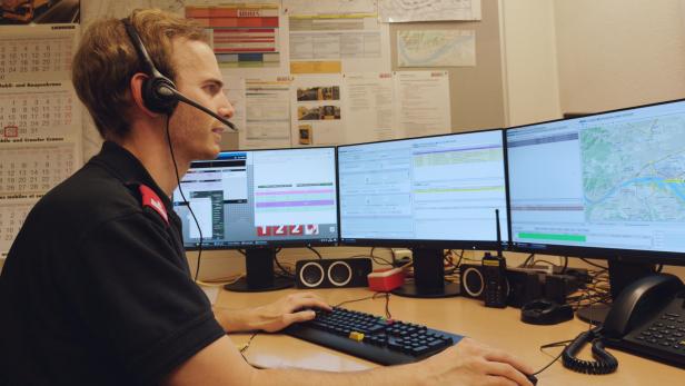 Ein Disponent arbeitet an mehreren Monitoren mit Karten und Einsatzplänen.