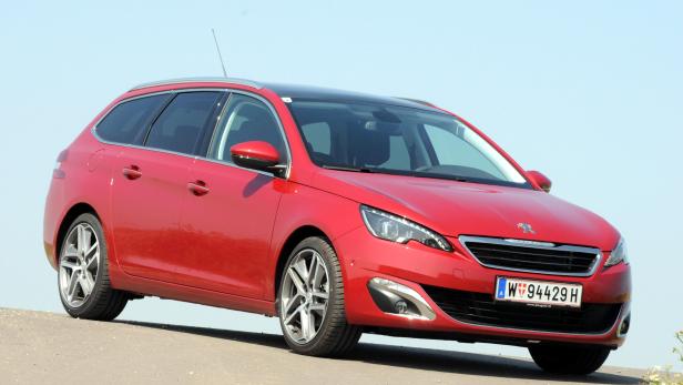 Ein roter Peugeot 308 SW Kombi steht auf einer asphaltierten Fläche.