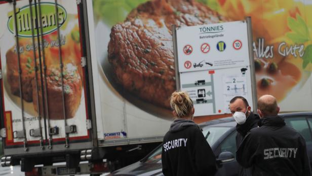 Security personell stands in front of a meat truck as the Toennies meat factory is reopening in Rheda-Wiedenbrueck