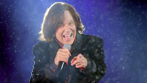 Jürgen Drews mit Mikrofon, bekleidet mit einem glitzernden Sakko, singt und zeigt auf den Betrachter.