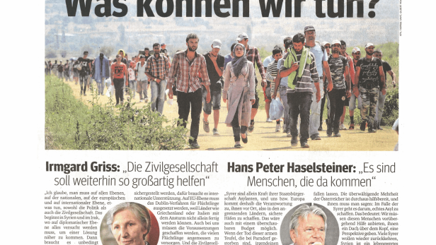 Eine Gruppe von Flüchtlingen geht auf einer staubigen Straße entlang.