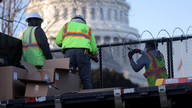 Workers install razor wire atop the unscalable fence surrounding the U.S. Capitol in Washington