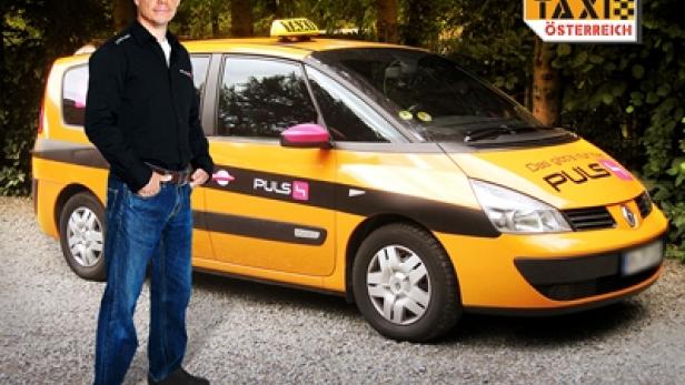 Ein Mann steht vor einem gelben „Quiz Taxi Österreich“-Taxi.