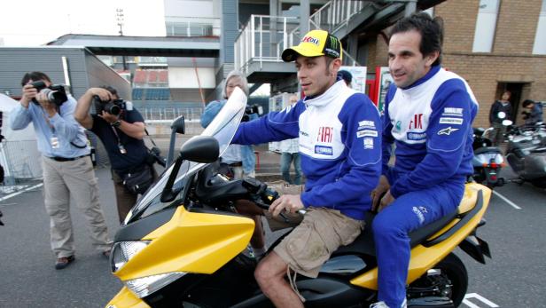 FILE PHOTO: Yamaha MotoGP rider Rossi of Italy rides a Yamaha TMAX motor scooter with his team manager Brivio prior to the the Japanese Grand Prix in Motegi