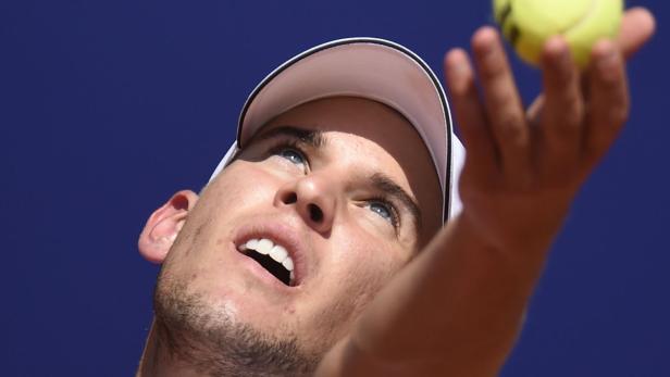 Ein Tennisspieler mit weißer Kappe wirft einen Tennisball in die Luft.