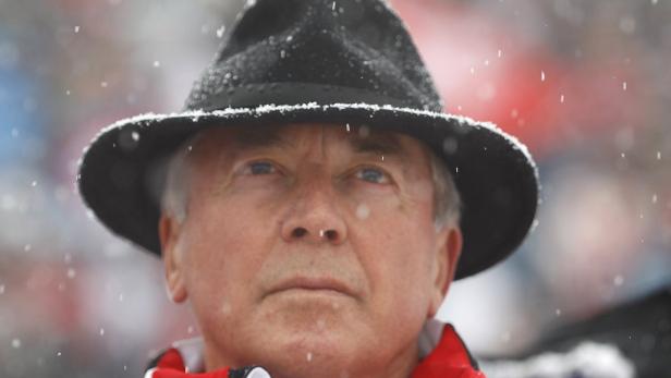 Ein Mann mit Hut steht im Schneefall.