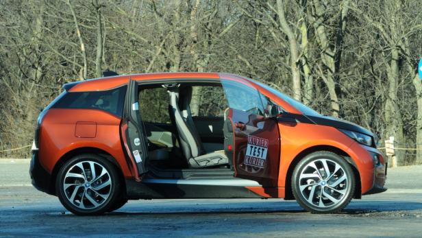 Ein orangefarbener BMW i3 mit geöffneten Türen steht im Freien.