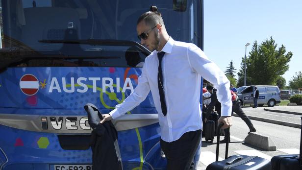 Ein Mann mit Sonnenbrille steigt aus einem Bus mit der Aufschrift „Austria“.