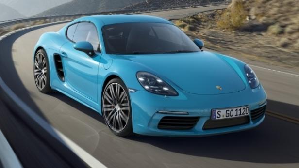 Ein türkisfarbener Porsche fährt auf einer kurvigen Straße.