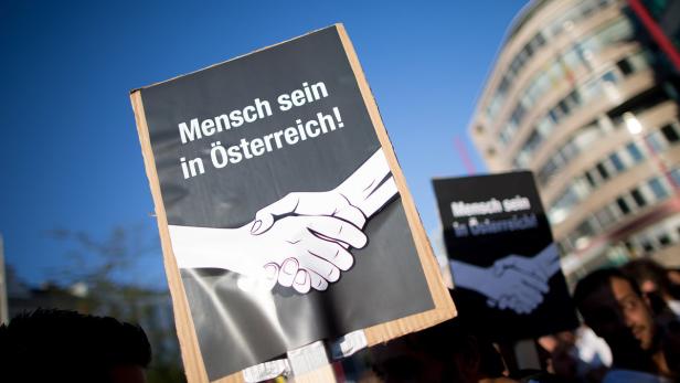 Eine Demonstration mit einem Schild, das „Mensch sein in Österreich!“ zeigt.