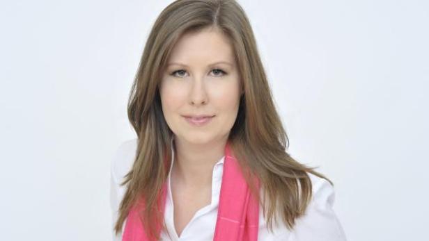 Eine Frau mit langen braunen Haaren und einem pinkfarbenen Schal lächelt.