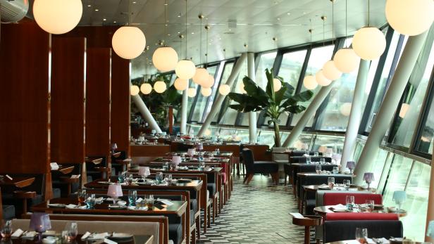 Ein elegantes Restaurant mit gedeckten Tischen und großen Fenstern.