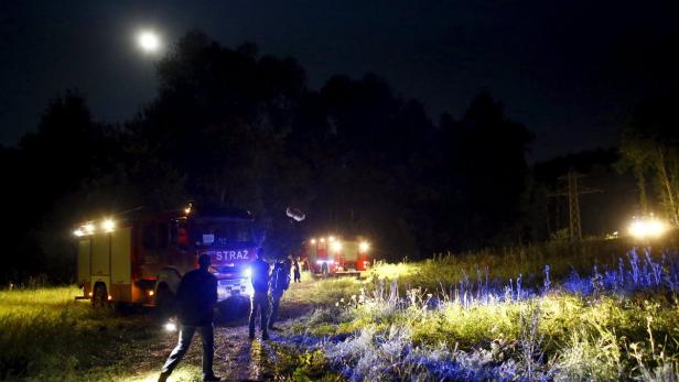People pass fire-fighter service cars, after an ev