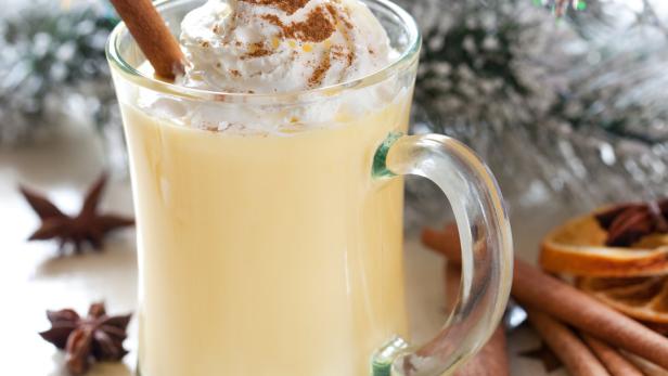 Ein Glas Eierpunsch mit Schlagsahne und einer Zimtstange als Garnitur.