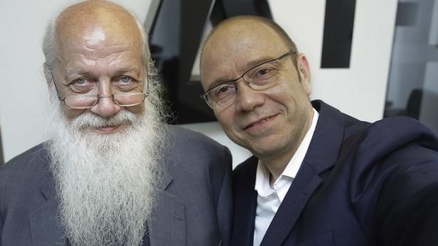 Zwei Männer in Anzügen posieren für ein Foto.