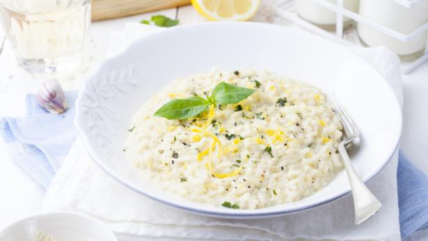 Risotto with lemon and fresh basil. White wooden background
