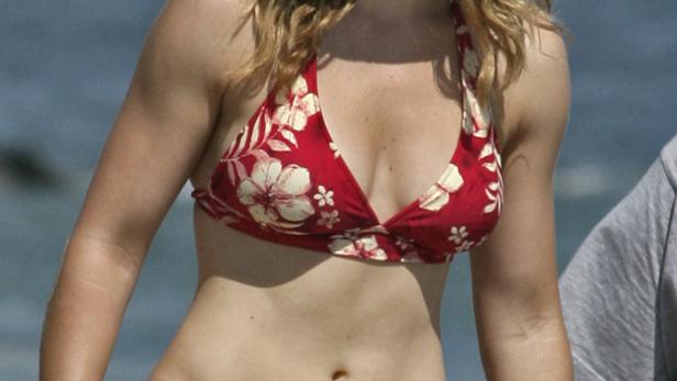 Jessica Biel am Strand in einem roten Bikini mit Blumenmuster und einem Strohhut.