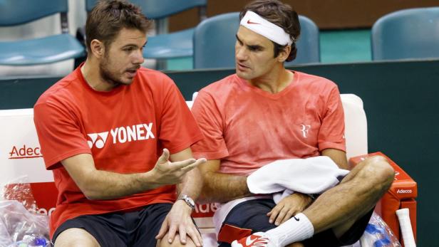 Roger Federer und Stan Wawrinka sitzen während eines Tennismatches auf der Bank und unterhalten sich.