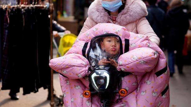 A woman wearing a face mask rides a bicycle with a child, following an outbreak of the coronavirus disease (COVID-19) in Wuhan