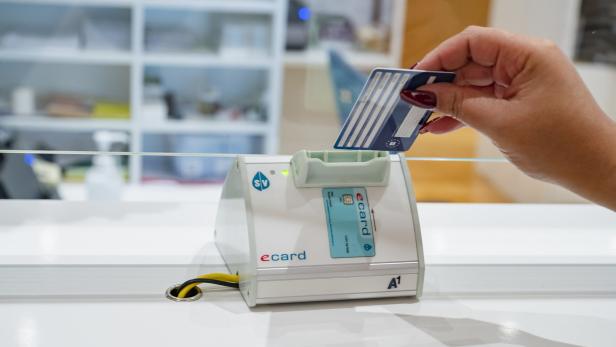 Eine Hand steckt eine Ecard in das Kartenlesegerät.