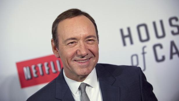 Kevin Spacey lächelt vor einem „House of Cards“-Hintergrund.