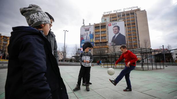 Children play football near some electoral campaign billboard in Pristina, Kosovo