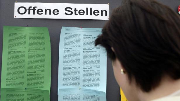 Eine Frau betrachtet eine Pinnwand mit dem Titel „Offene Stellen“.