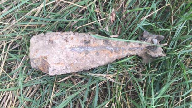 Eine alte, rostige Granate liegt im Gras.