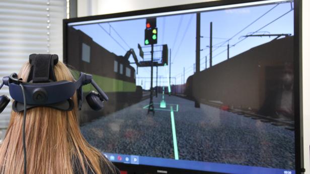 Jugendliche mit VR-Brille vor Monitor mit Bahnanlage