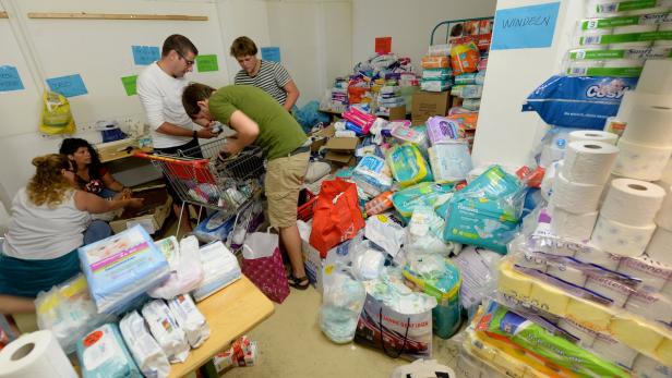 Mehrere Helfer sortieren Spenden von Windeln und Hygieneartikeln in einem Lagerraum.