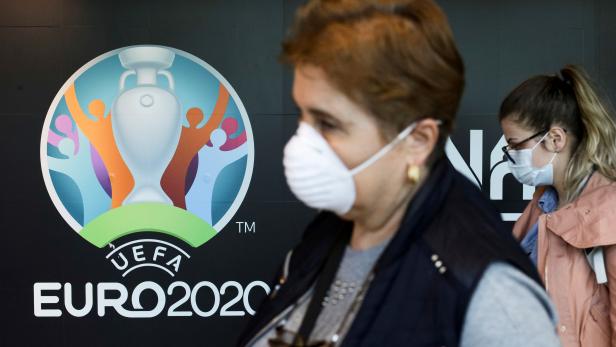 FILE PHOTO: Travellers pass by a logo of the 2020 UEFA European Football Championship displayed on a wall inside Bucharest Henri Coanda International Airport