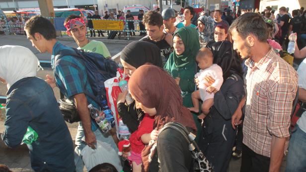 Eine Gruppe von Menschen, darunter Frauen mit Kopftüchern und Kinder, steht beieinander.