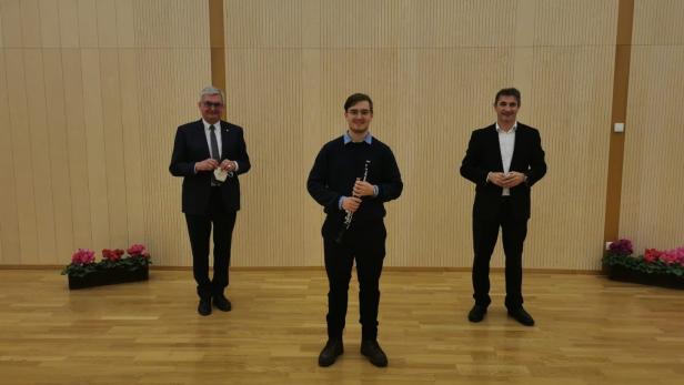 Bürgermeister Alfred Riedl (l.) und Musikschulleiter Markus Holzer (r.) gratulieren Paul Blüml zur neuen Stelle im Orchester.