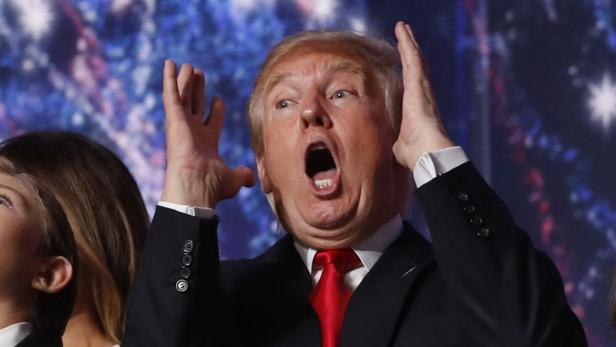 Donald Trump reißt mit geöffnetem Mund die Arme hoch.