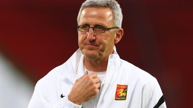 Ein Mann mit Brille und weißer Jacke mit dem Logo von Admira Wacker.