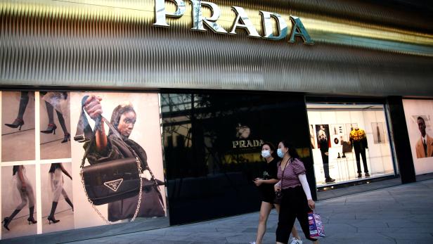 FILE PHOTO: FILE PHOTO: People wearing face masks following the COVID-19 outbreak walk past a store of Italian luxury brand Prada at shopping area in Beijing
