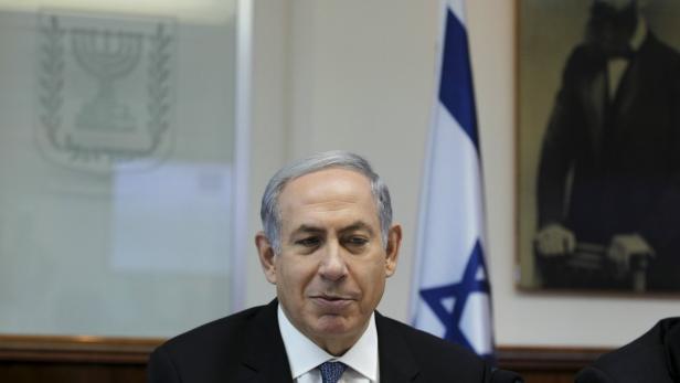 Benjamin Netanjahu vor einer israelischen Flagge und einem Porträt.