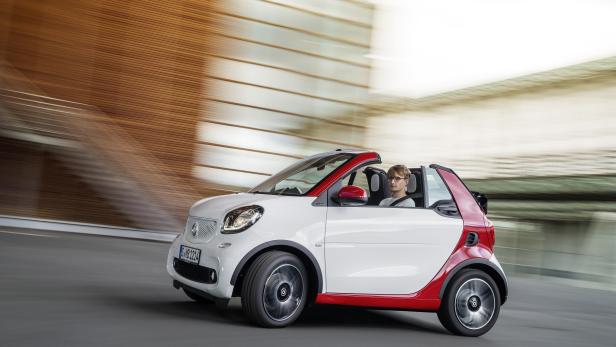 Ein weiß-roter Smart fährt auf einer Straße.