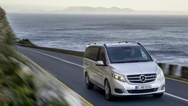 Ein silberner Mercedes-Benz Van fährt auf einer Küstenstraße.