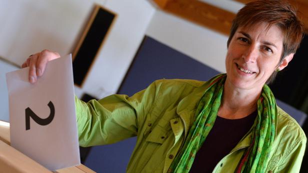 Eine Frau wirft einen Stimmzettel mit der Nummer 2 in eine Wahlurne.