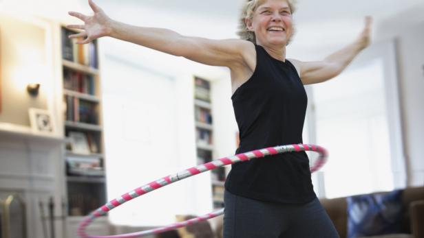  Ältere schlanke Frau hat Spaß an Bewegung mit Hula Hoop-Reifen.