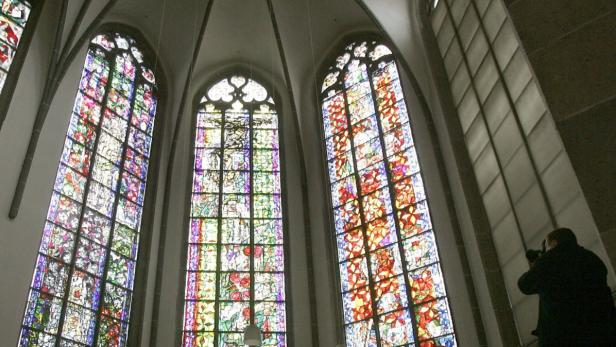 Ein Fotograf nimmt am Montag (17.12.2007) die zwei neuen farbigen Fenster (links und Mitte) in der Mitte des Machabäer-Chors in der Kirche St. Andreas in Köln auf. Seit Mitte der 90er Jahre gab es Überlegungen, den Chor mit Fenstern von Professor Markus Lüpertz auszustatten. Im Dezember 2005 konnte das erste Fenster (r) mit dem Thema &quot;Märtyrer der Machabäer&quot; eingesetzt werden. Zwei weitere sind nun hinzugekommen. Foto: Jörg Carstensen dpa/lnw +++(c) dpa - Bildfunk+++