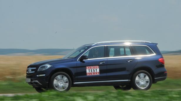Ein blauer Mercedes-Benz Kombi mit „Kurier Test Kurier“-Aufkleber fährt auf einer Landstraße.