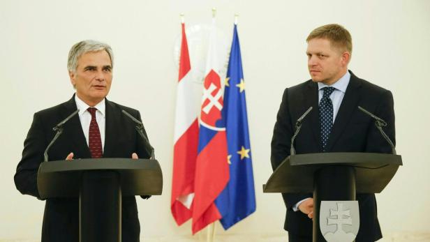 Zwei Männer stehen an Rednerpulten vor Flaggen der EU und der Slowakei.