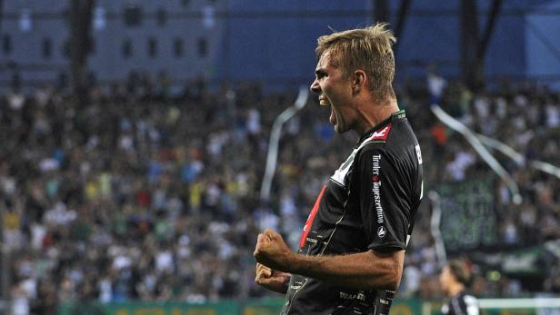 Ein Fußballspieler jubelt mit geballten Fäusten vor einer Zuschauermenge.