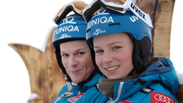 Zwei Skirennläuferinnen mit blauen Helmen und Skibrillen posieren für ein Foto.