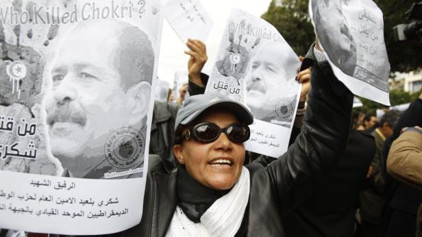 A woman chants slogans and holds pictures of assassinated leftist politician Chokri Belaid during a demonstration against the Islamist Ennahda movement in Tunis February 23, 2013. REUTERS/Zoubeir Souissi (TUNISIA - Tags: CIVIL UNREST POLITICS)