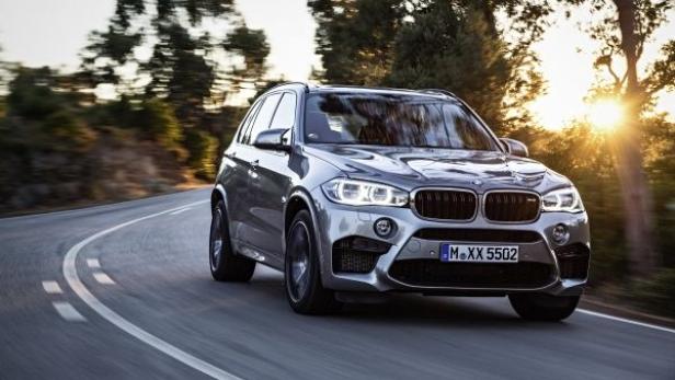 Ein silberner BMW X5 fährt auf einer kurvigen Straße.