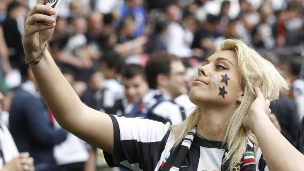 A Juventus&#039; supporter take a picture of herself on the pitch at the end of the team&#039;s Italian Serie A soccer match against Palermo at the Juventus stadium in Turin May 5, 2013. Juventus won Serie A for the second season running on Sunday, clinching the title with a 1-0 win over Palermo. REUTERS/Stefano Rellandini (ITALY - Tags: SPORT SOCCER) TEMPLATE OUT